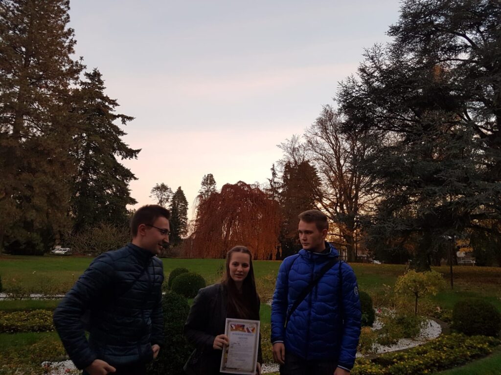 Drei Personen stehen in einem Park bei Sonnenuntergang und halten ein Dokument in der Hand.