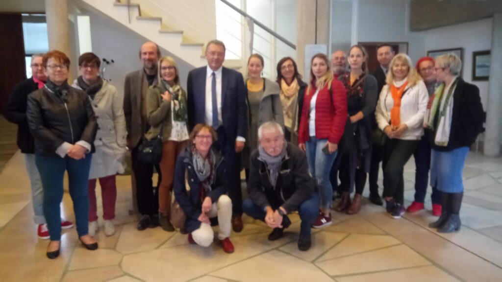 Gruppe von Menschen posiert in einem Gebäude, einige lächeln für das Foto.