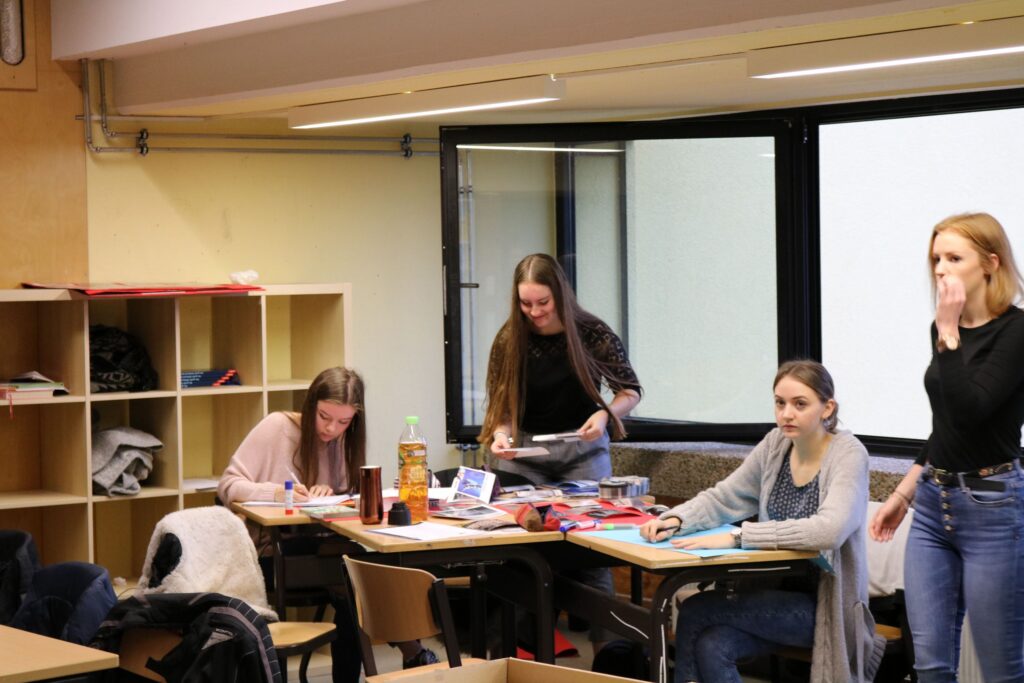 Schülerinnen arbeiten in einem Klassenraum an ihren Projekten.