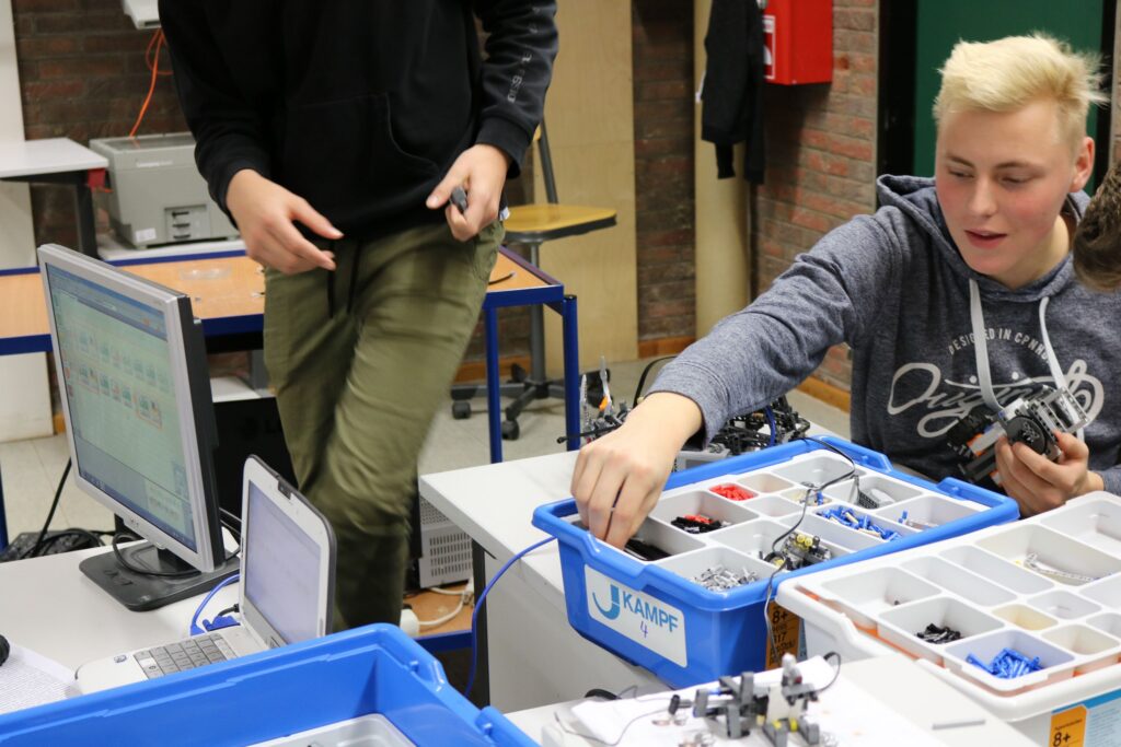 Schüler arbeitet an einem Tisch mit Robotik-Bauteilen und Computer.