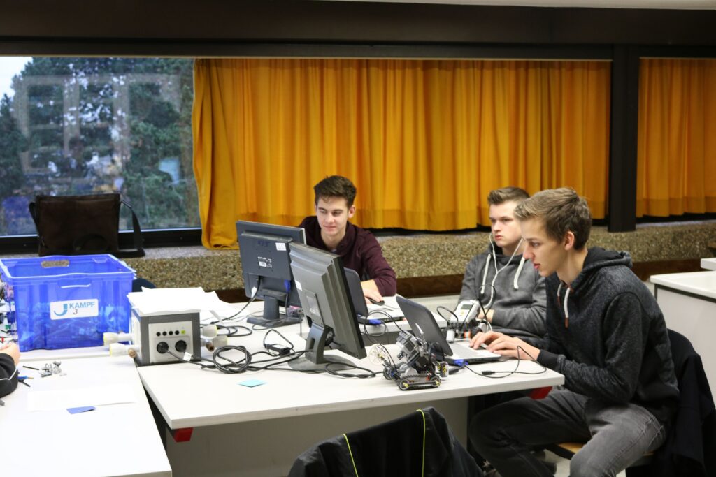 Drei Schüler arbeiten konzentriert an Computerplätzen in einem Klassenraum.