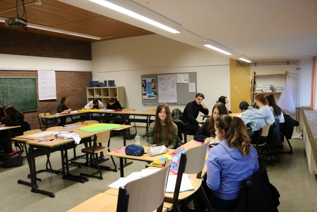 Schüler arbeiten an Tischen in einem Klassenraum.