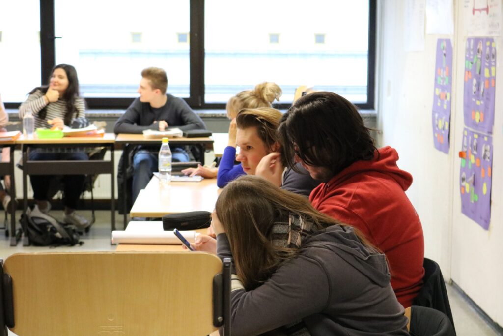Schülerinnen und Schüler sitzen in einem Klassenraum und arbeiten.