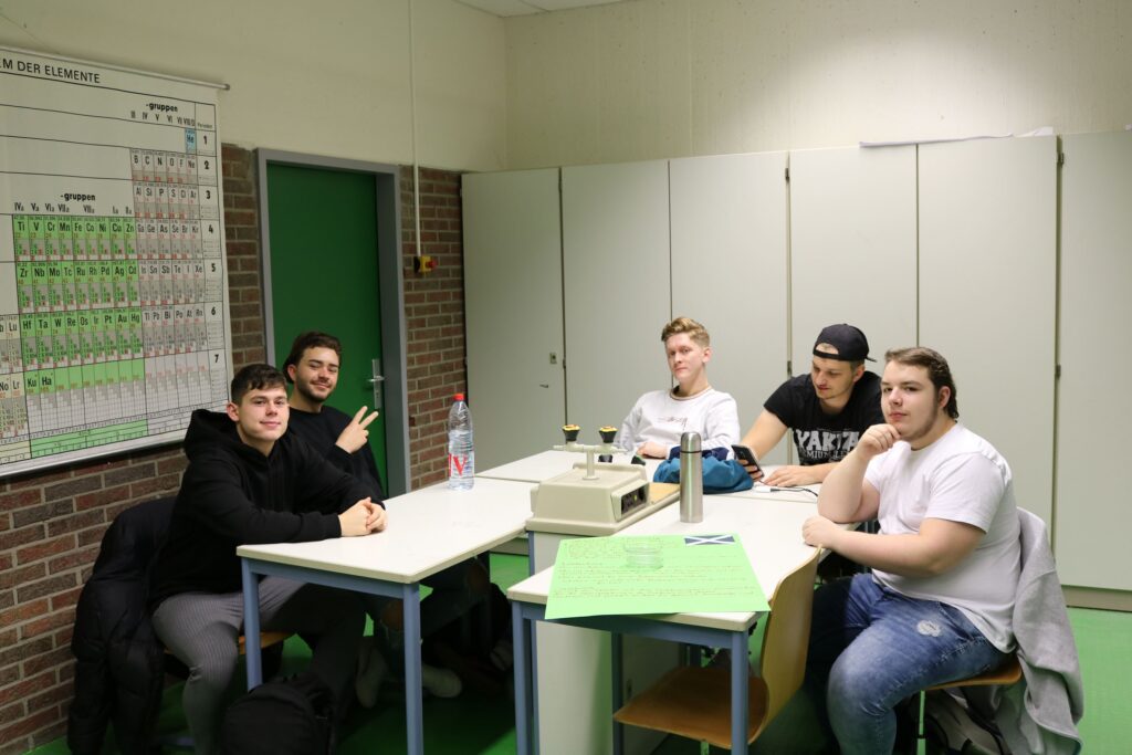 Fünf Schüler sitzen an einem Tisch in einem Klassenraum.