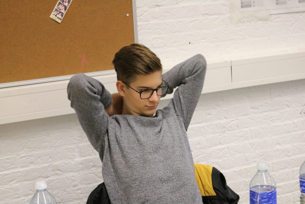 Schüler sitzt entspannt mit hinter dem Kopf verschränkten Armen.