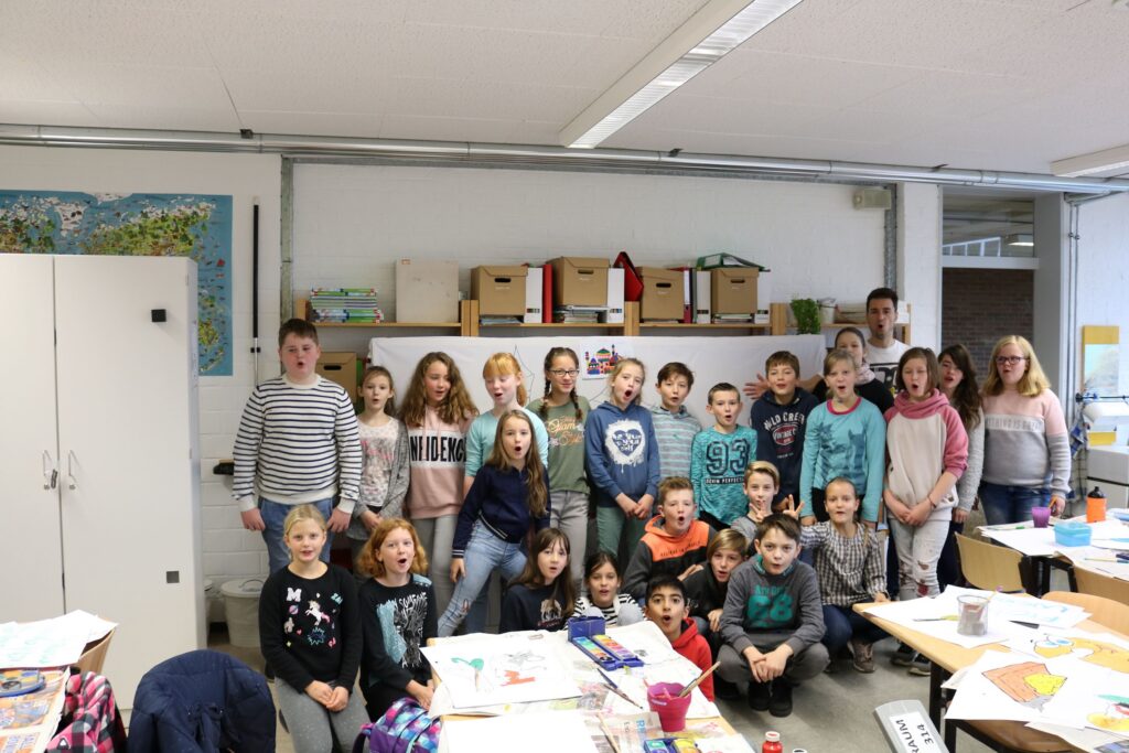 Schülergruppe in einem Klassenzimmer, zahlreiche Bastelmaterialien auf den Tischen.