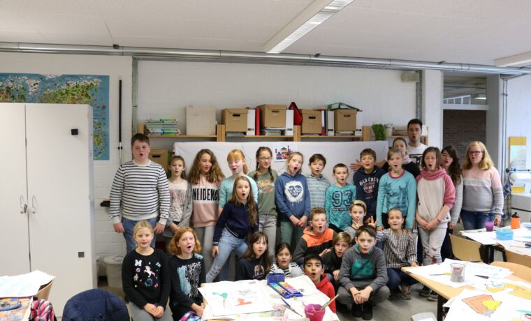 Schülergruppe in einem Klassenzimmer, zahlreiche Bastelmaterialien auf den Tischen.