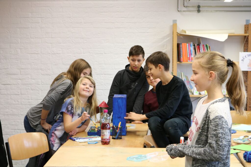 Kinder arbeiten gemeinsam an einem Tisch in einem Klassenraum.