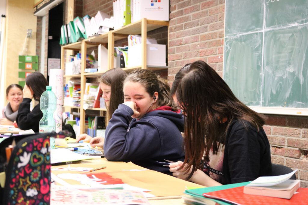 Schülerinnen arbeiten konzentriert an Tischen in einem Klassenraum.
