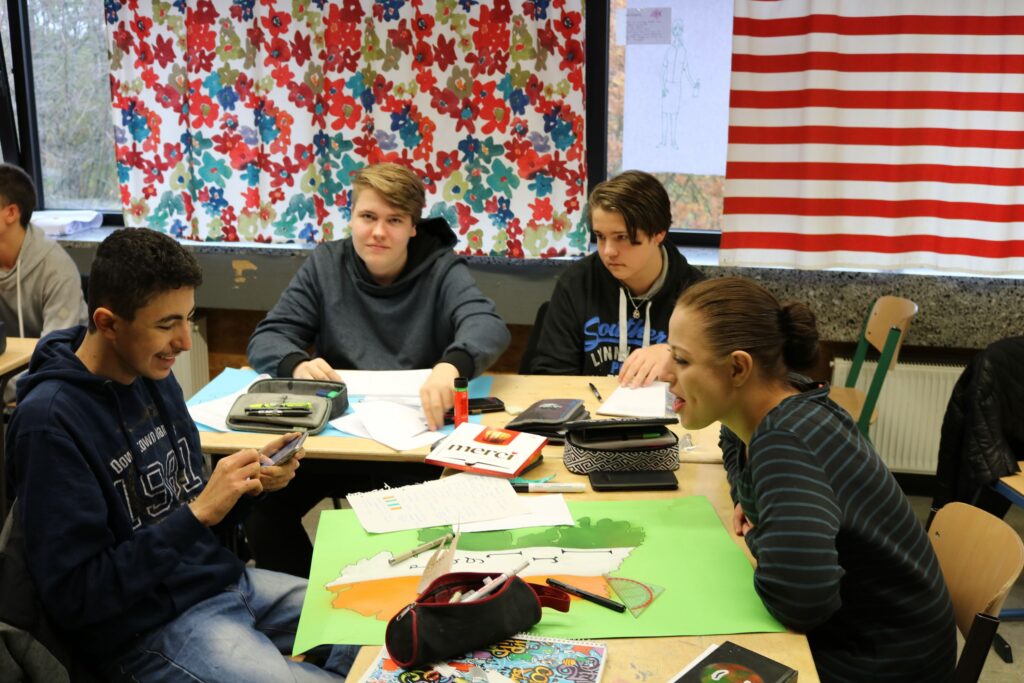 Vier Schüler sitzen an einem Tisch und arbeiten an ihren Projekten.