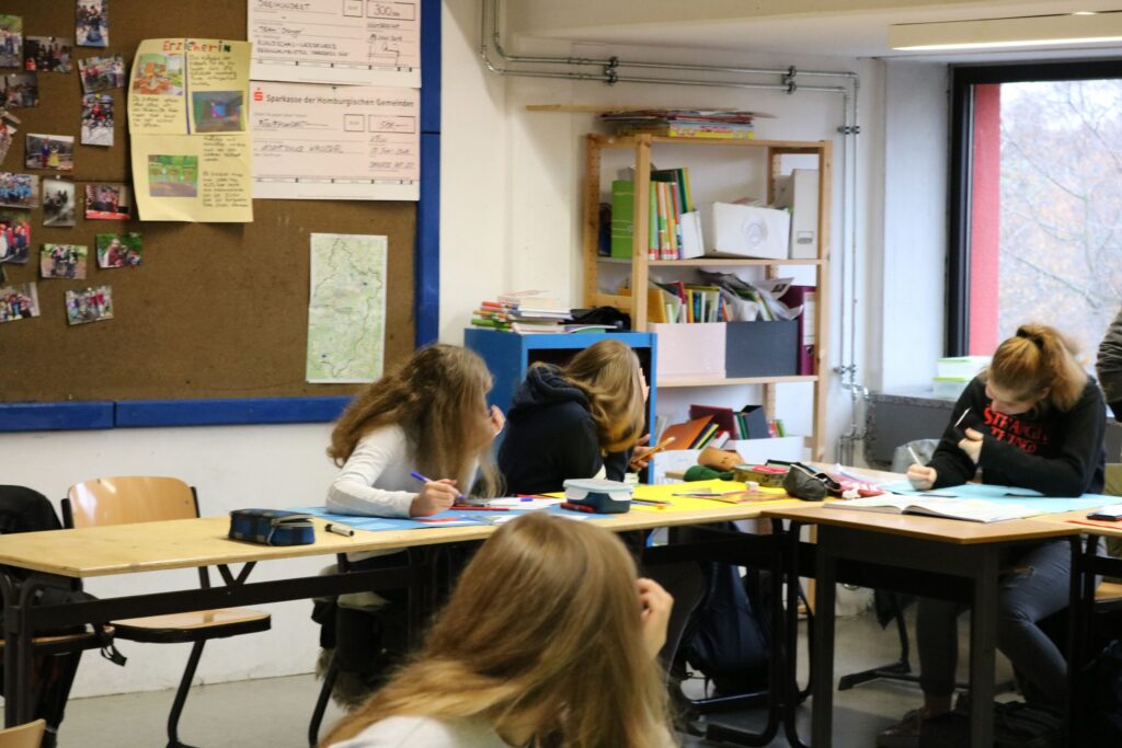 Schülerinnen arbeiten konzentriert an ihren Schulaufgaben in einem Klassenraum.