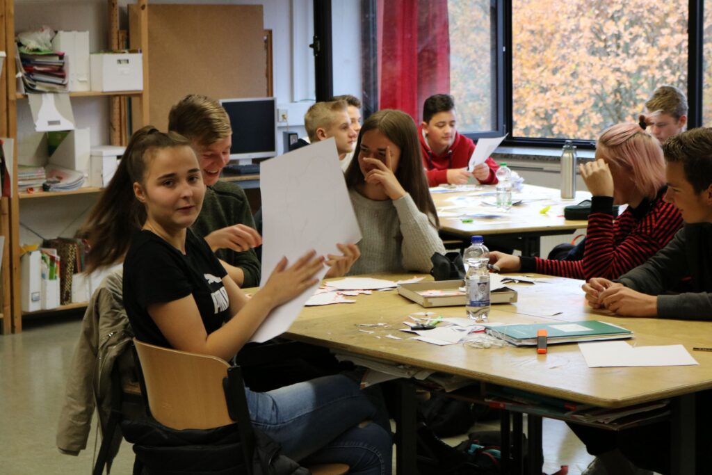 Schülerinnen und Schüler arbeiten an Tischen in einem Klassenraum.