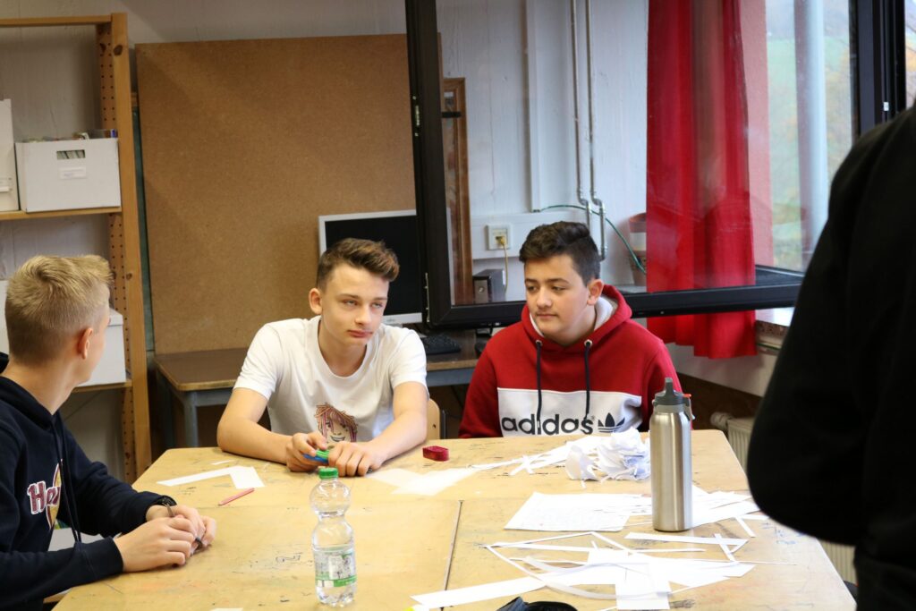 Schüler sitzen an einem Tisch in einem Klassenraum und arbeiten zusammen.
