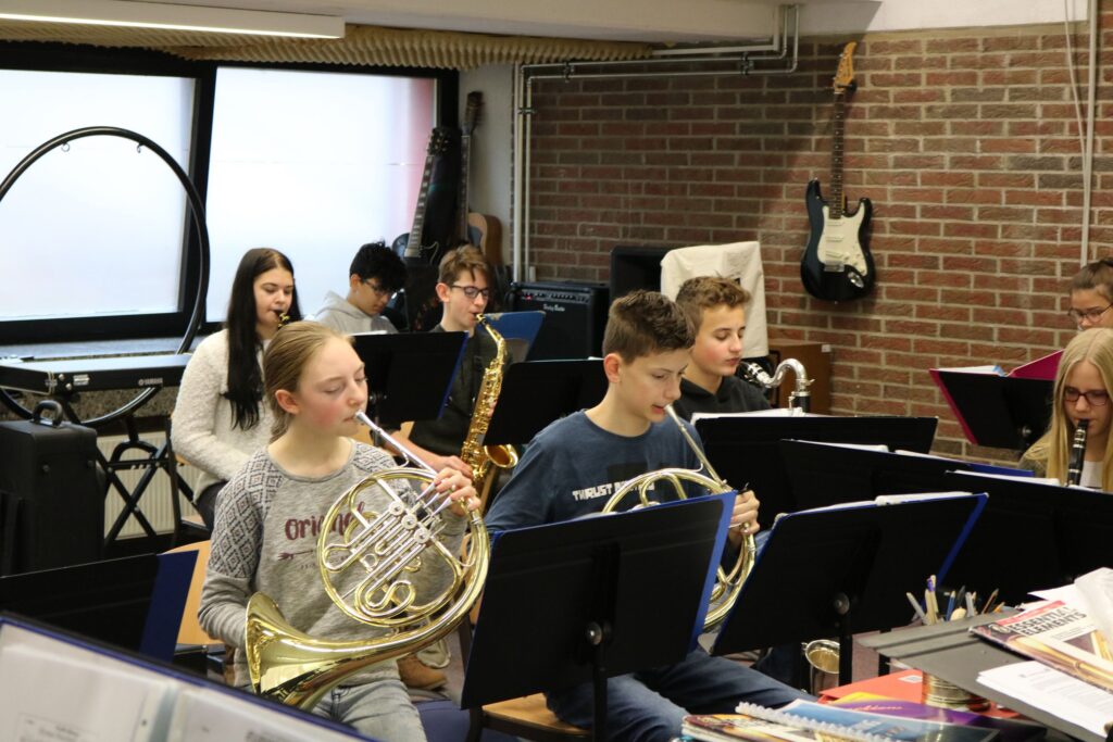 Schüler spielen in einem Musikraum verschiedene Blasinstrumente.