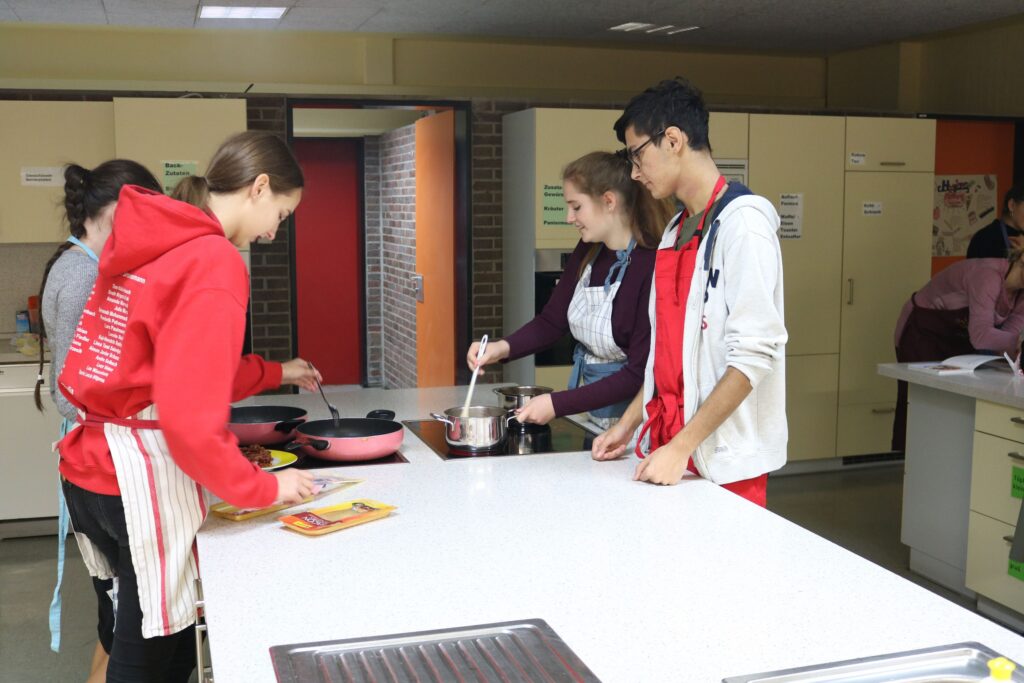 Schüler bereiten gemeinsam in einer Schulküche Gerichte zu.