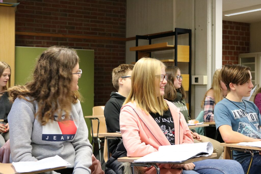 Schüler sitzen in einem Klassenzimmer und hören aufmerksam zu.