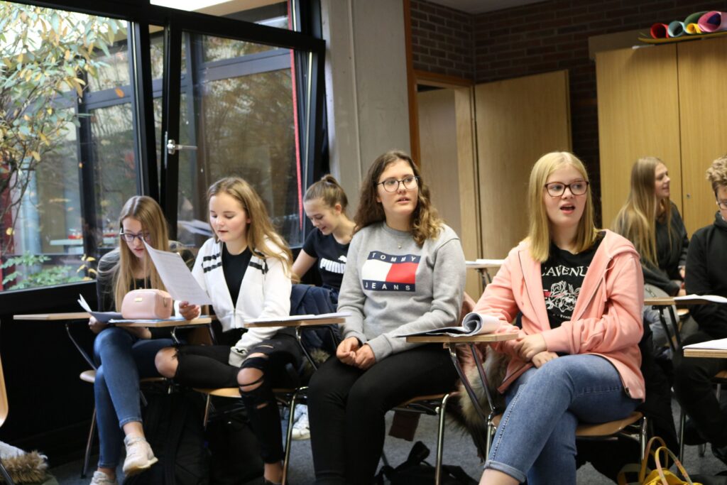 Schülerinnen sitzen im Klassenzimmer und hören aufmerksam zu.