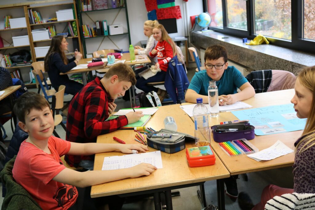 Schüler arbeiten an Tischen in einem Klassenraum.