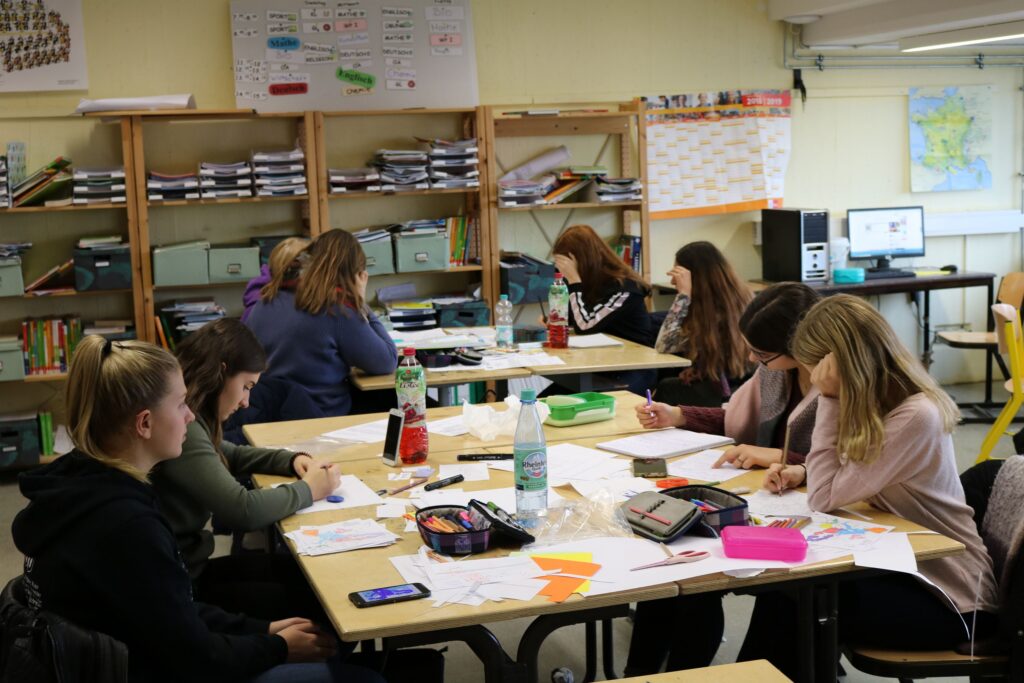 Schülerinnen arbeiten konzentriert an Tischen im Klassenraum.