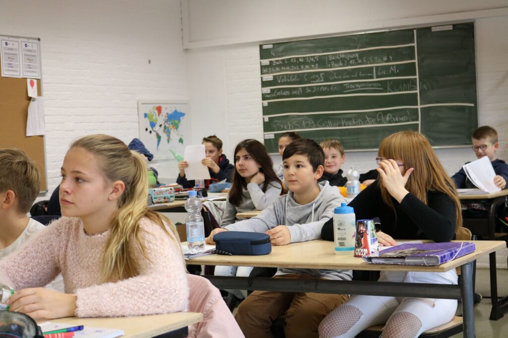 Schülerinnen und Schüler sitzen im Klassenraum und hören aufmerksam zu.
