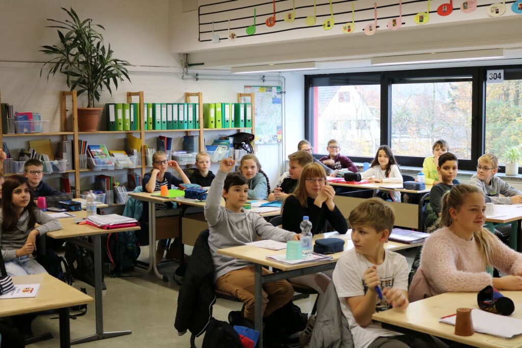 Schülerinnen und Schüler sitzen im Klassenzimmer und beteiligen sich am Unterricht.