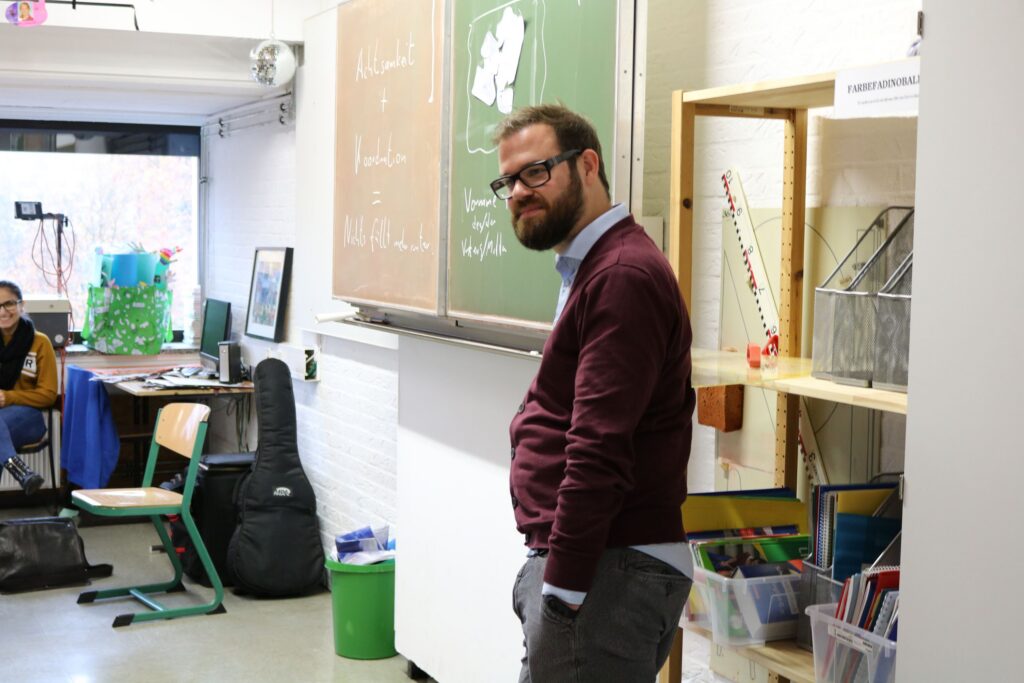 Lehrer steht vor einer Tafel in einem Klassenraum.