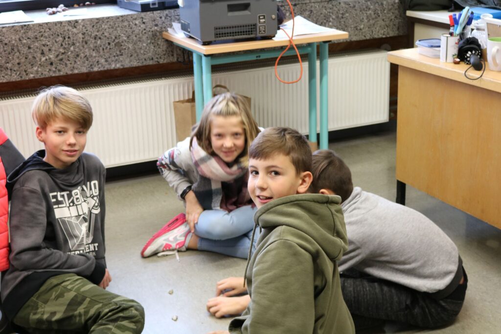 Schüler sitzen auf dem Boden und spielen im Klassenraum.