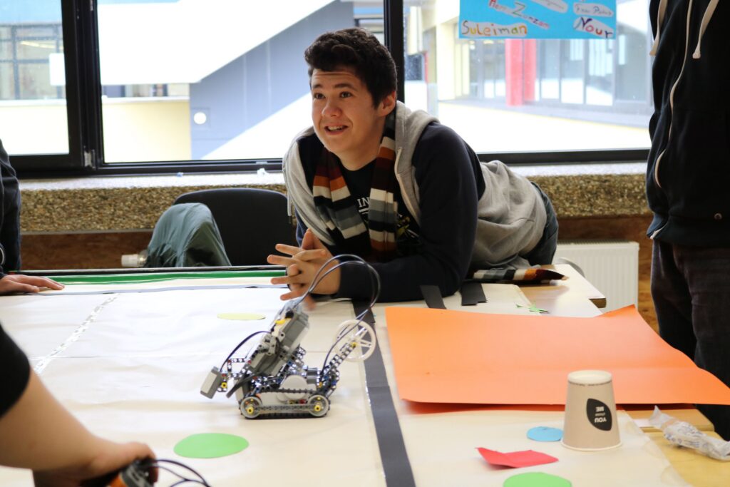 Schüler arbeitet an einem Robotikprojekt mit einem Roboter und Materialien.
