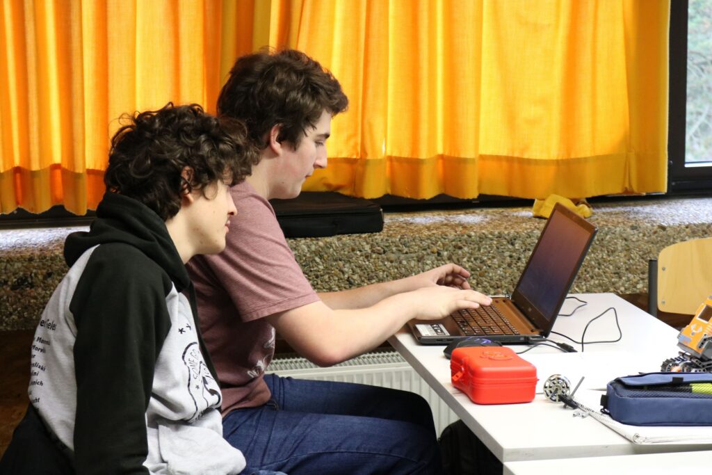 Zwei Schüler arbeiten gemeinsam an einem Laptop in einem Klassenzimmer.