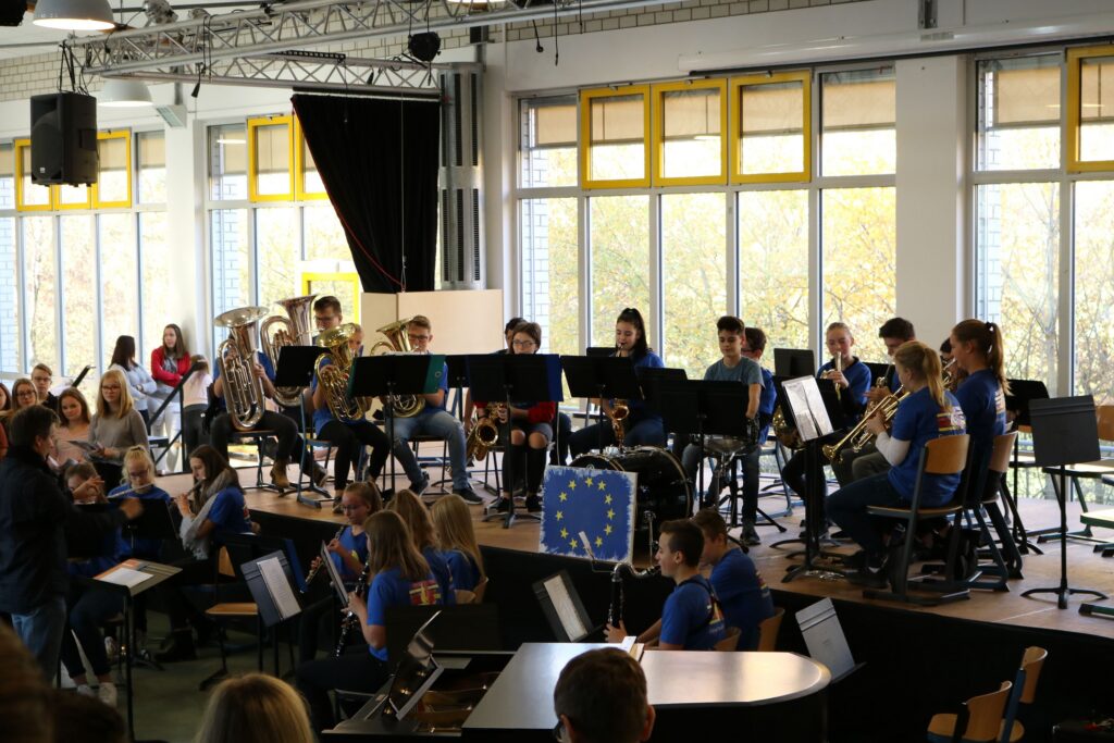 Schüler spielt im Schulkonzert in einem großen Raum mit Fenstern.