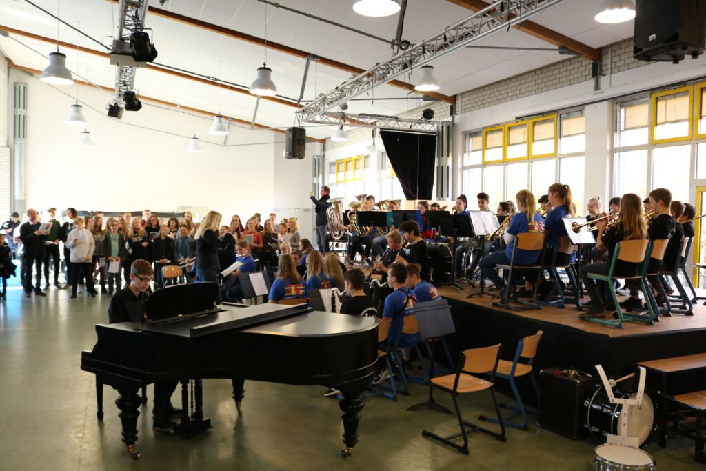 Schüler bei einem Konzert, Orchestermusiker und Klavier auf der Bühne.