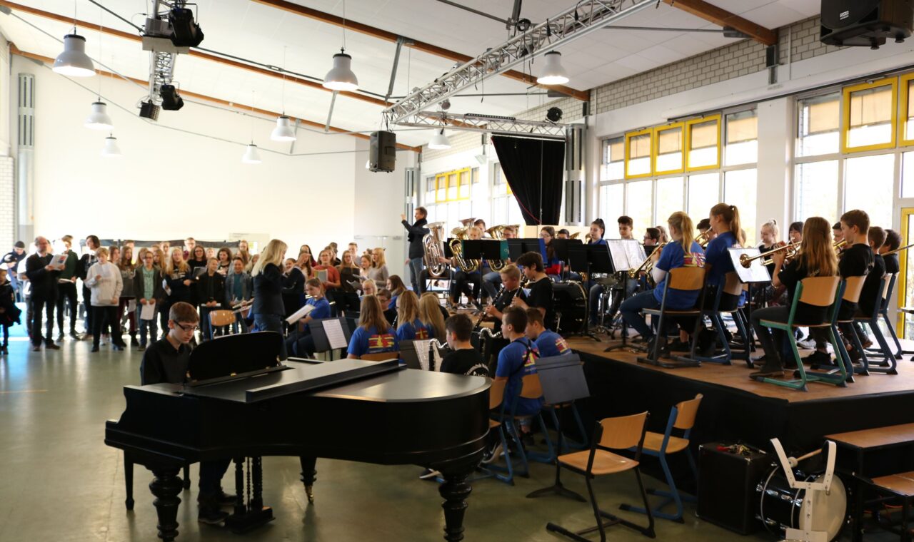 Schüler bei einem Konzert, Orchestermusiker und Klavier auf der Bühne.