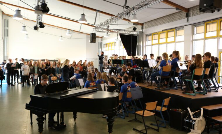 Schüler bei einem Konzert, Orchestermusiker und Klavier auf der Bühne.