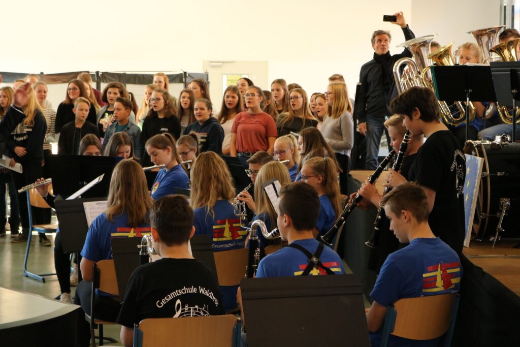 Schülerinnen und Schüler singen und spielen gemeinsam in einem Musikprojekt.