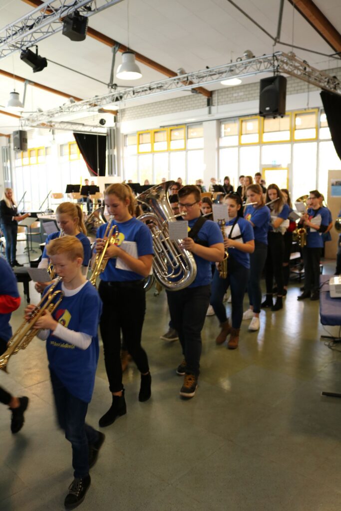 Schüler mit Instrumenten marschieren in einem Musikraum.