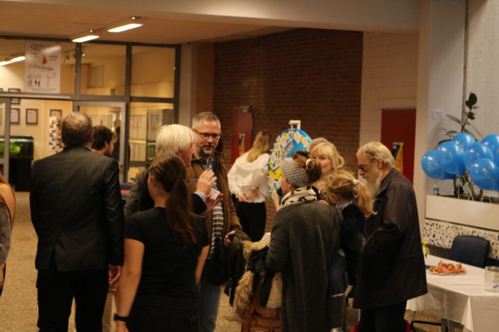 Menschen in fröhlicher Atmosphäre bei einem Event in der Schule.