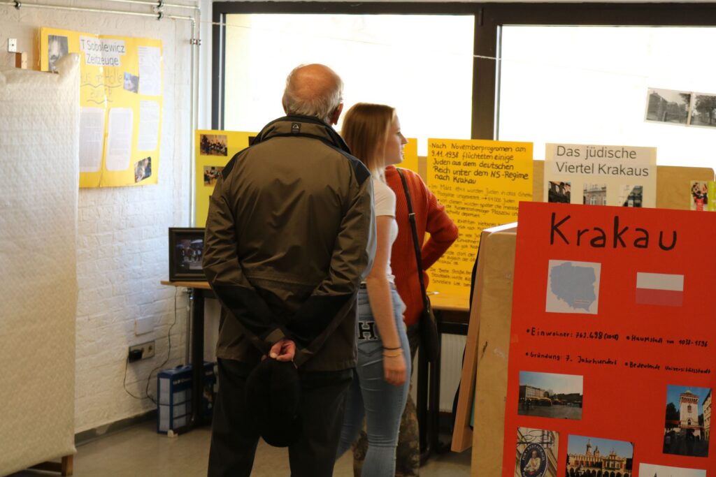 Zwei Personen betrachten Informationsplakate in einem Ausstellungsraum.