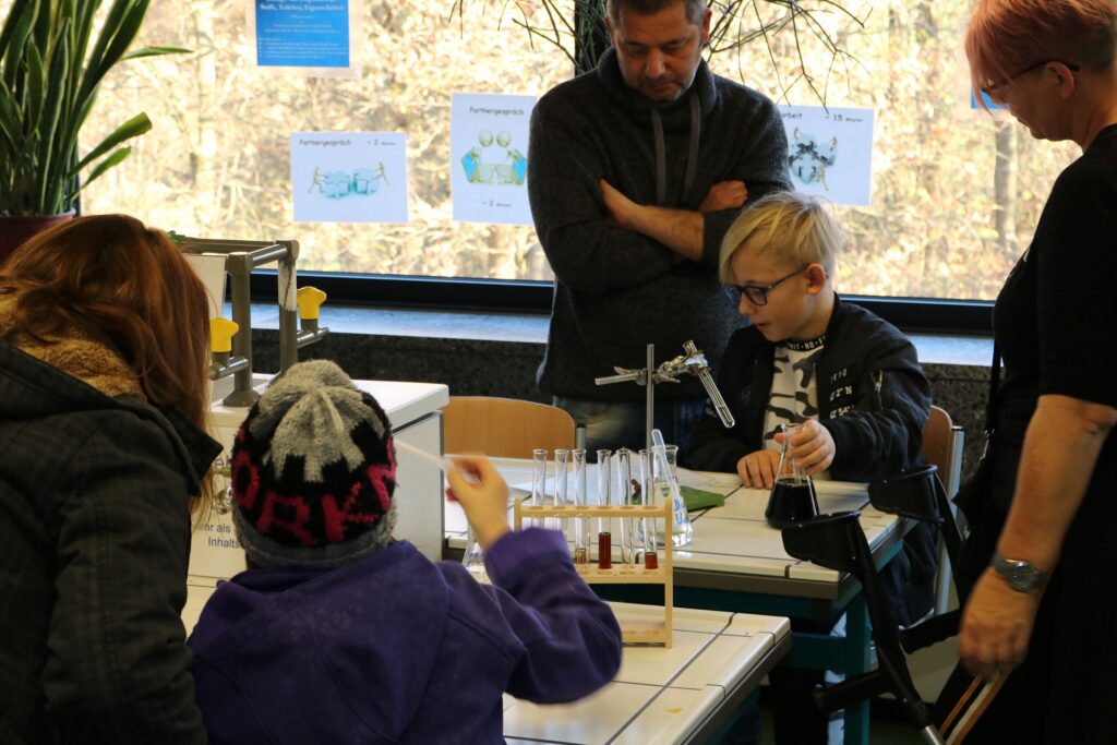 Schülerinnen und Schüler experimentieren am Tisch im Klassenzimmer.