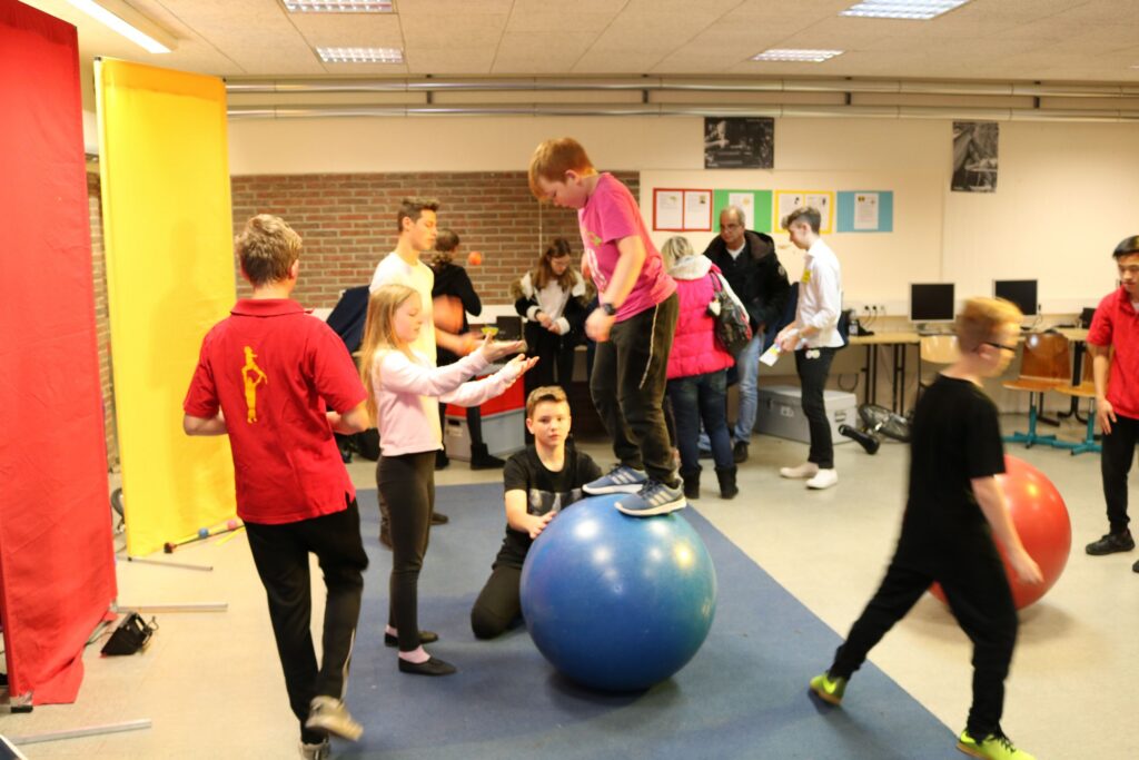 Schüler balancieren auf Bällen in einem Klassenraum mit Zuschauern.
