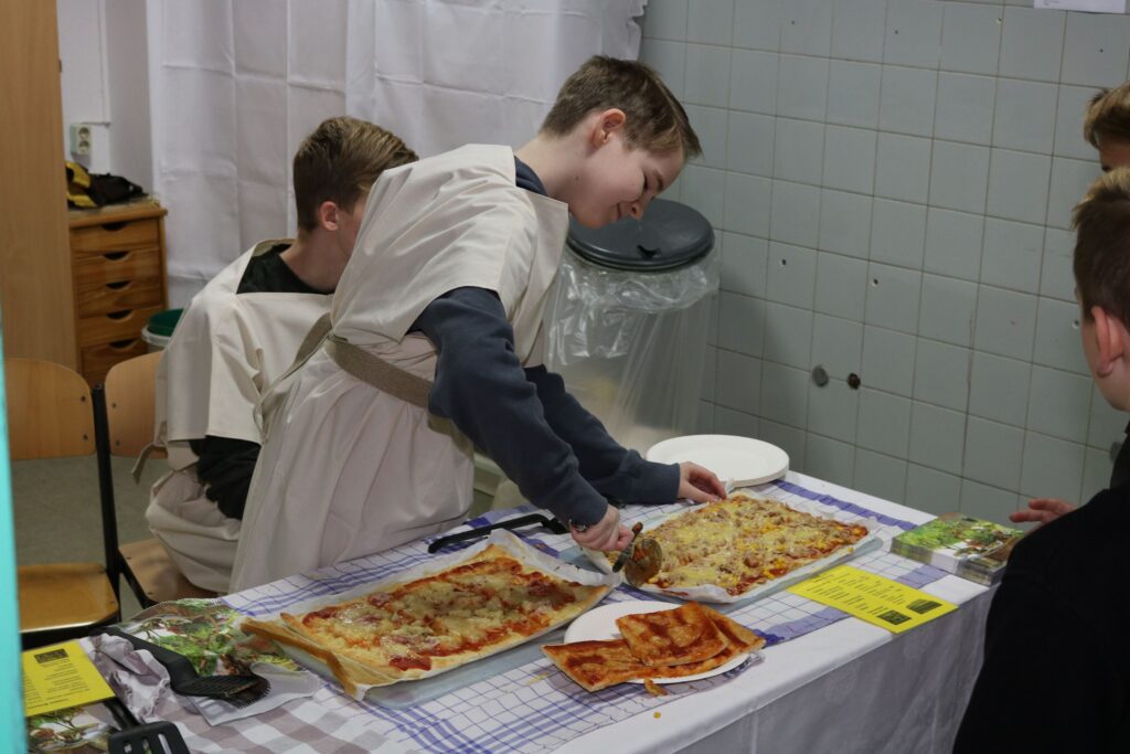 Schüler servieren Pizza an einem Tisch in einer Schulveranstaltung.