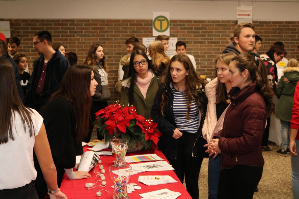 Schülerinnen und Schüler informieren sich an einem Stand bei einer Veranstaltung.
