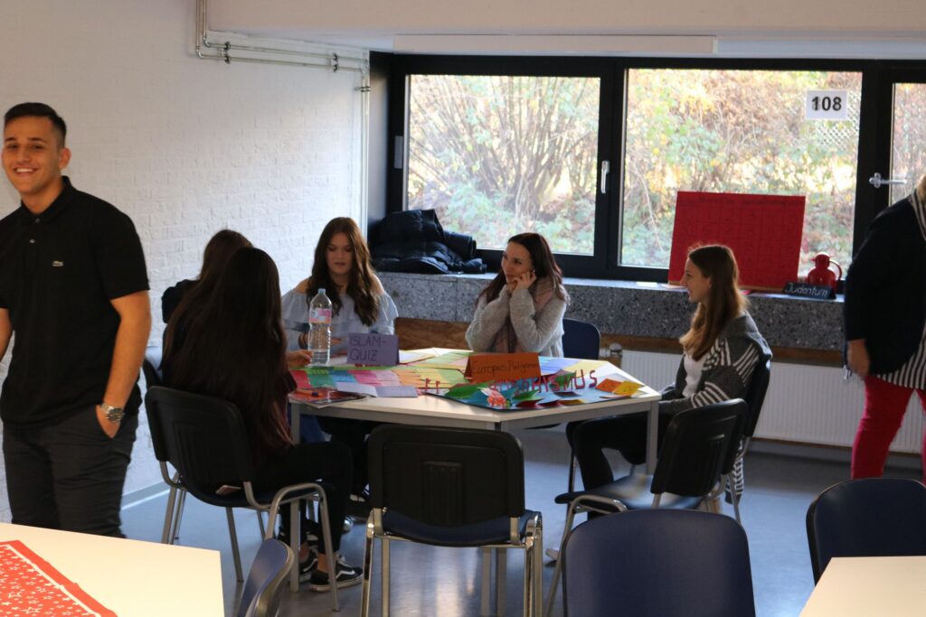 Schülerinnen und Schüler arbeiten an einem Tisch in einem Klassenraum.