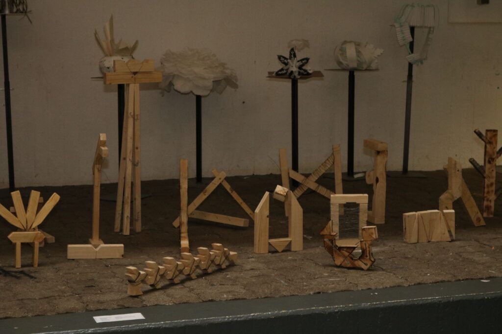 Holzkonstruktionen auf Podesten in einem Ausstellungsraum.