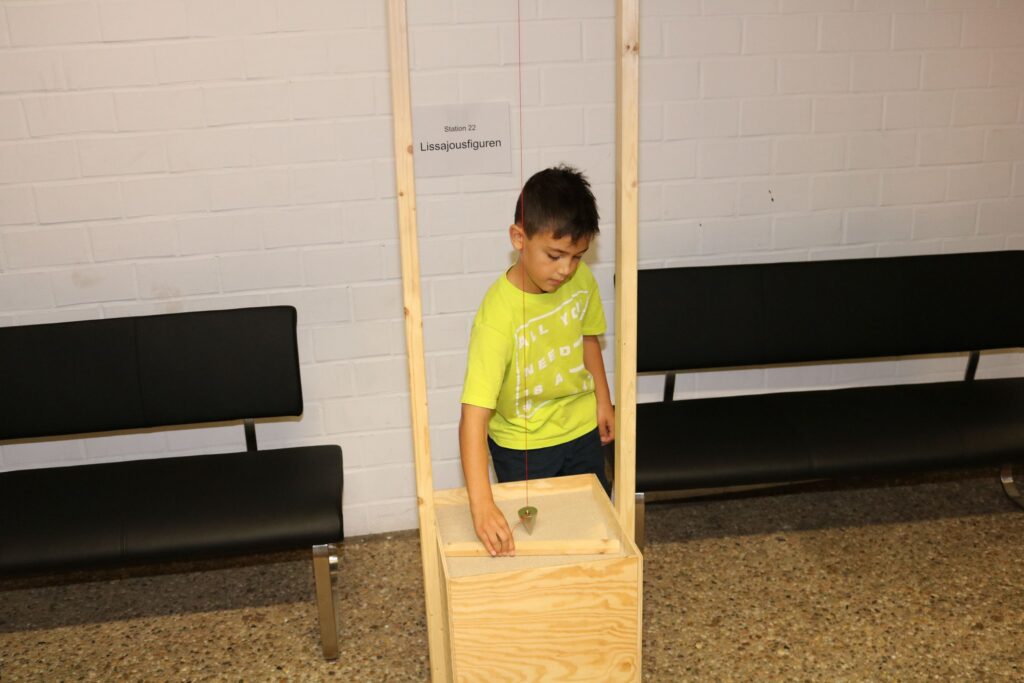 Ein Junge interagiert mit einem Holzkasten in einem Foyer.