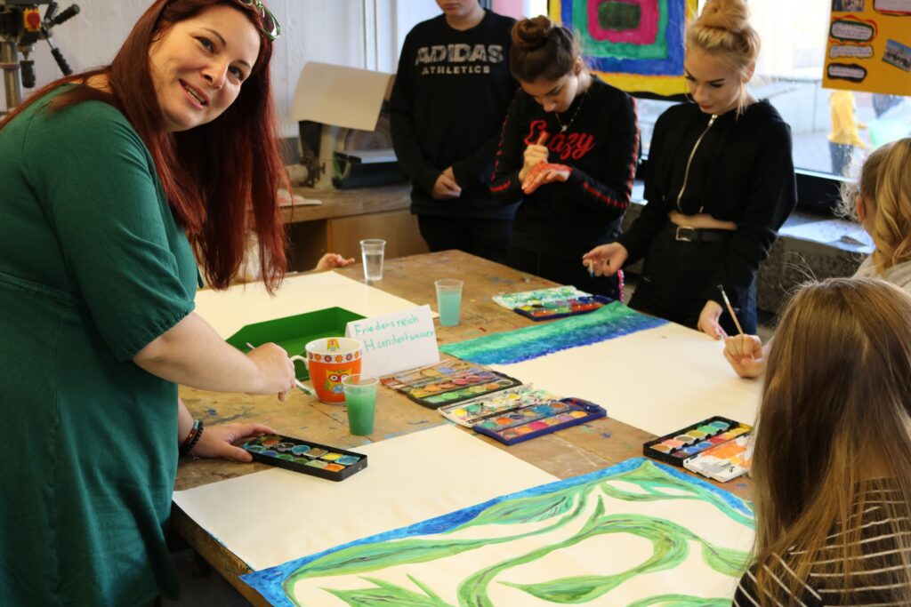 Lehrerin und Schüler beim Malen in einem Kunstraum.