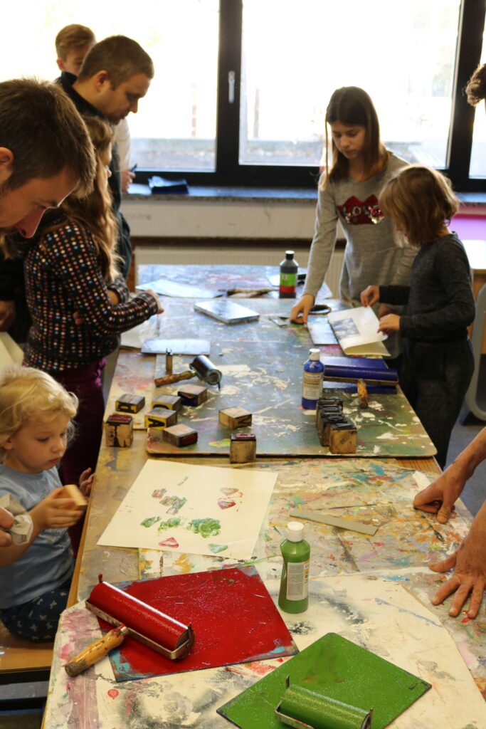 Gruppenaktivität im Klassenzimmer mit Kindern beim Malen und Basteln.