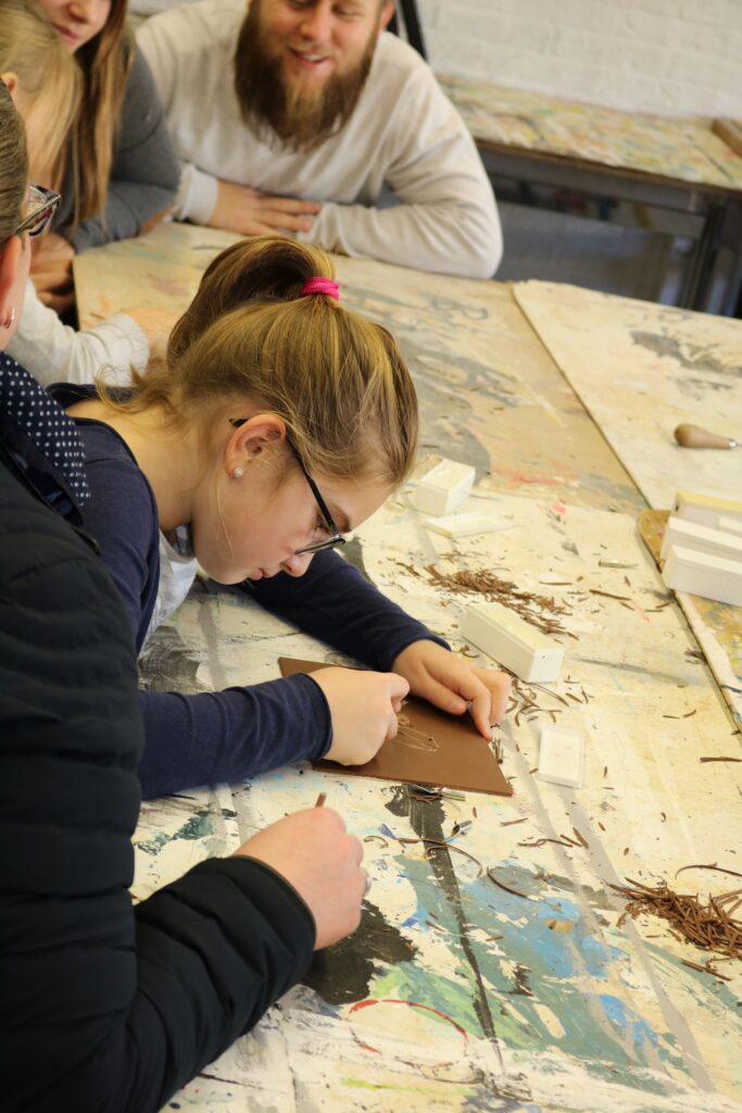 Schülerin arbeitet konzentriert an einem Kunstprojekt am Tisch.