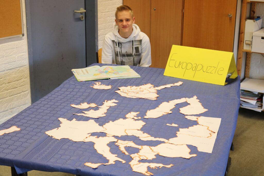 Schüler sitzt an einem Tisch mit einer Karte von Europa und umreißten Ländern.