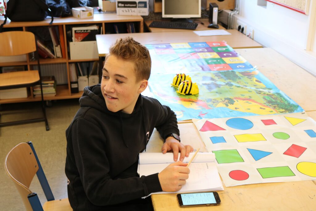 Schüler sitzt an einem Tisch mit Arbeitsmaterialien und einem Tablet.