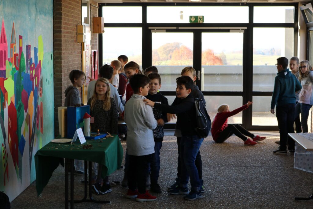 Schüler stehen in einem Flur vor einer bunten Wandmalerei.